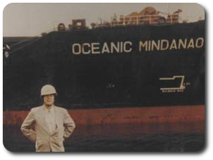 Photo of the Japanese panamax shipping vessel, Oceanic Mindanoa, owned by the Sumitomo Corporation, Tokyo, Japan with Garnac employee, Kazuyoshi (Kyle) Uchida standing next to it in the port of Chiba, Japan.
